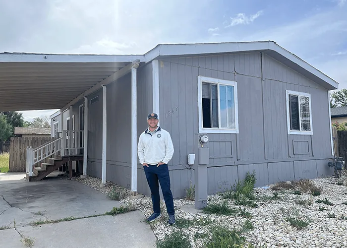 Kyle Ridge standing outside a gray manufactured home he purchased in the Reno area